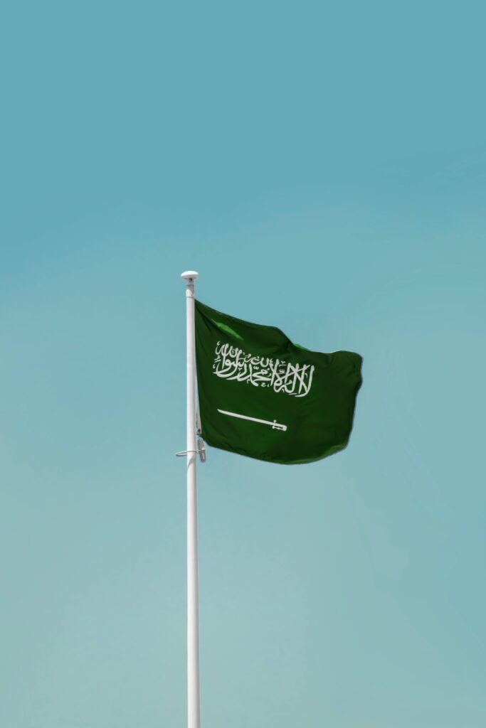 pexels-photo-13884417-13884417 National flag of Saudi Arabia waving on a flagpole against a clear blue sky in Riyadh.